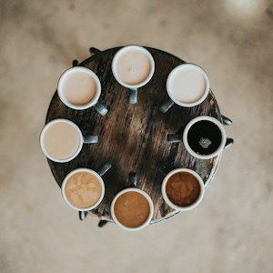 Dutch Bros Candy Cane Mocha: What It Is, How to Order and 2026 Status Overhead view of coffee drinks in white cups on a round wooden table, Dutch Bros Candy Cane Mocha guide
